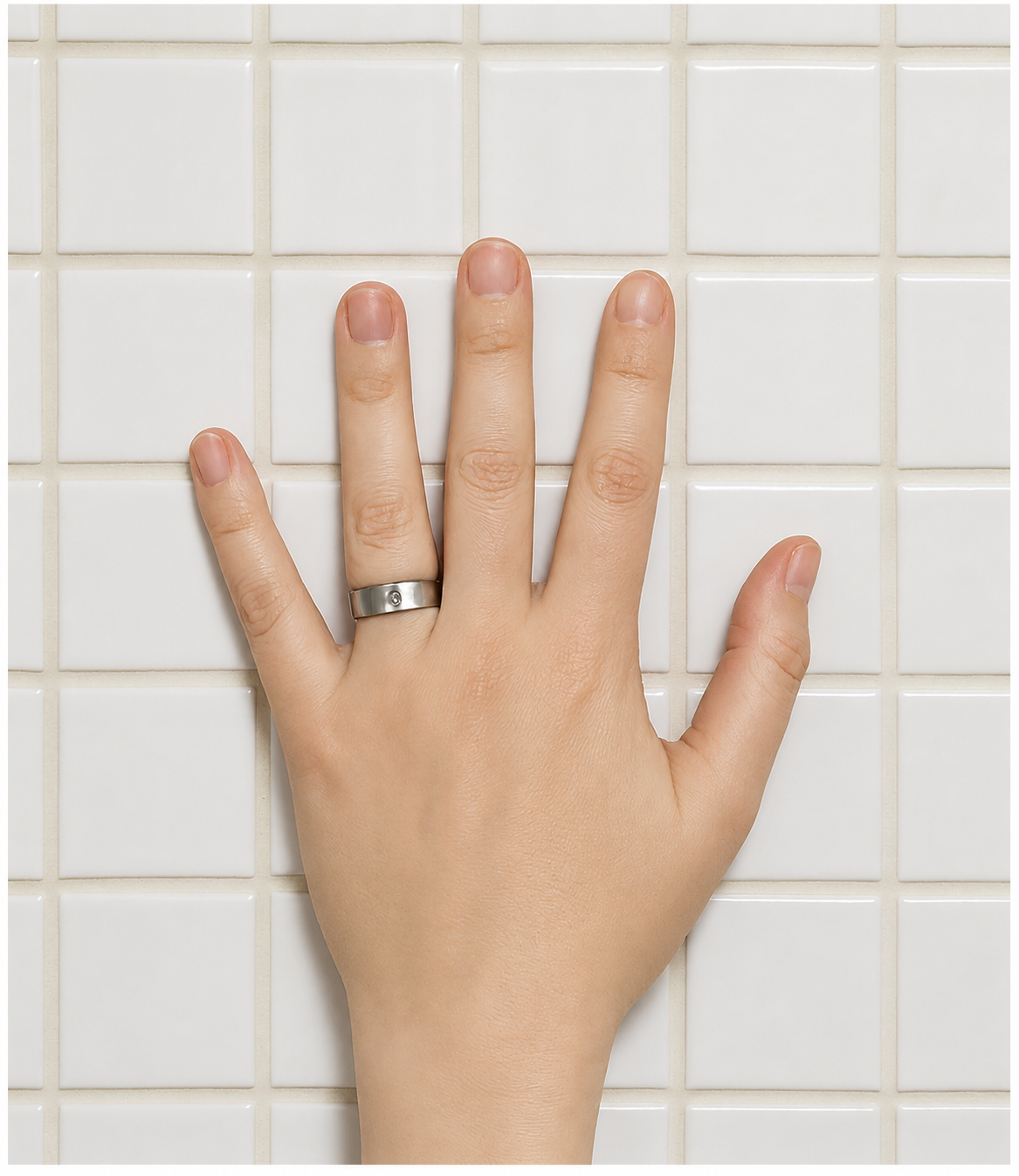 Hand mit Ring auf weißen Kacheln